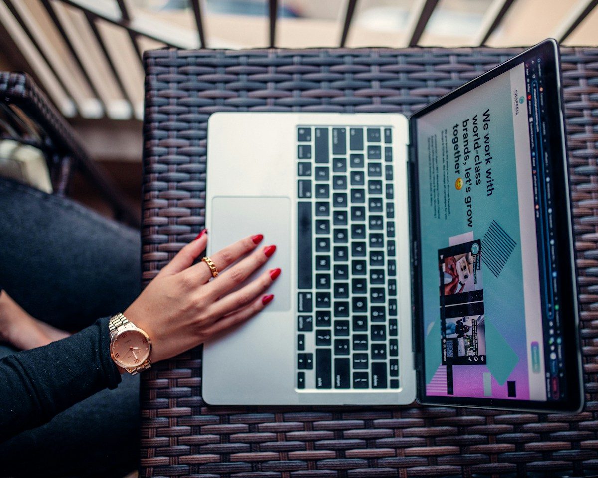 Person using a laptop showing a business website, viewed from above